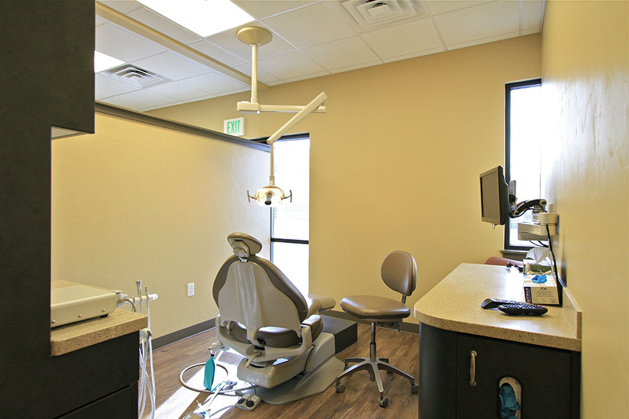 The image depicts a dental office interior with equipment and furniture typically found in such a setting.