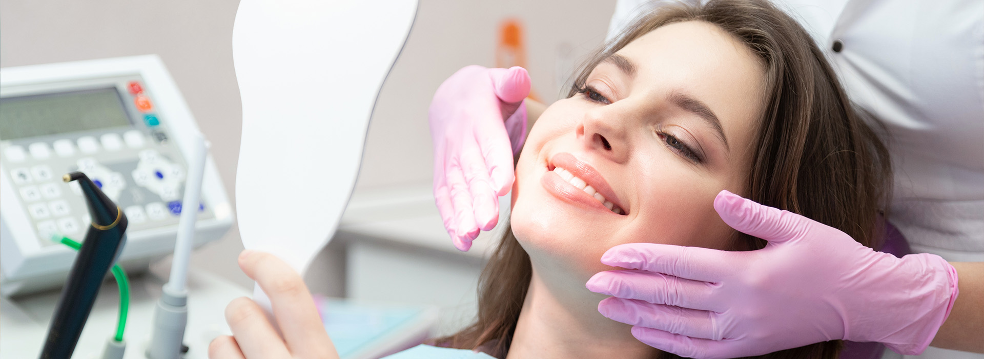 The image shows a woman receiving dental care with a smiling expression while seated in a dental chair.