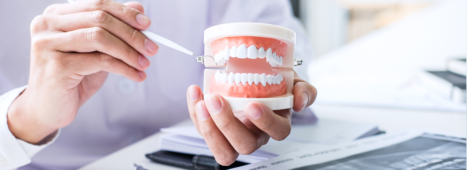 An individual holding a toothbrush with toothpaste over a paperwork table.